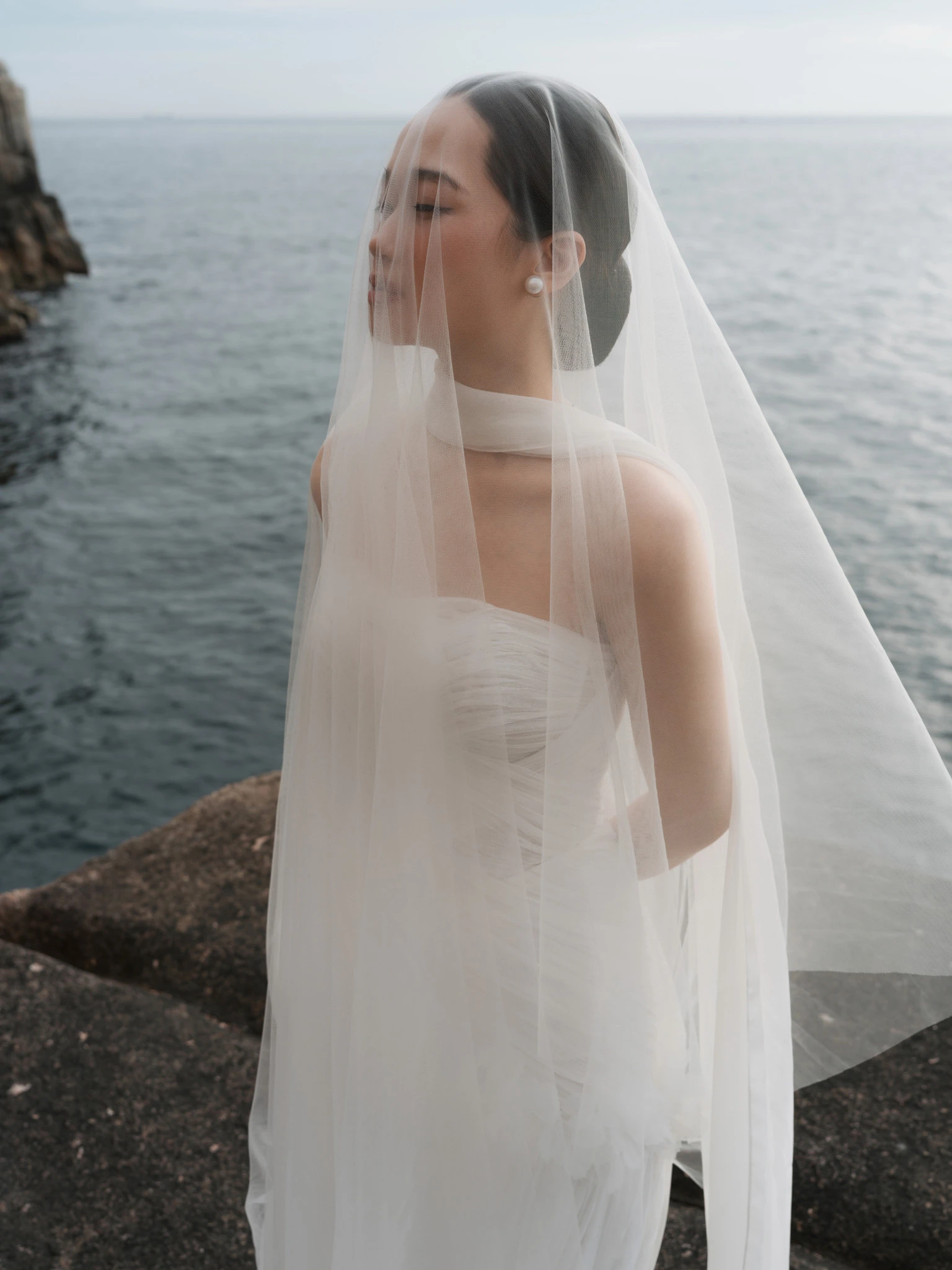Linh dưới khăn voan nhìn về phía biển.