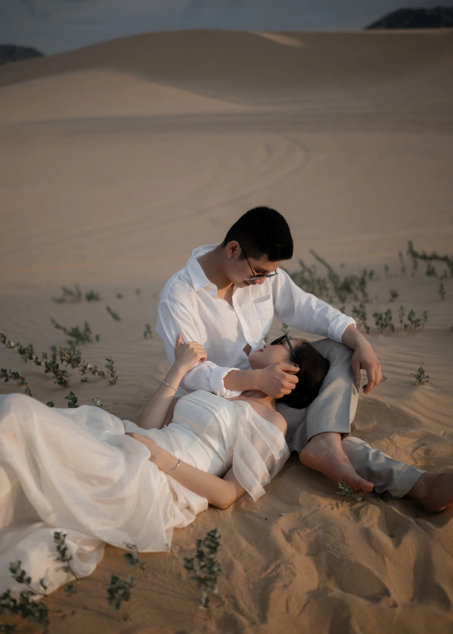 Linh và Bình ngồi tựa bên nhau trên cát.