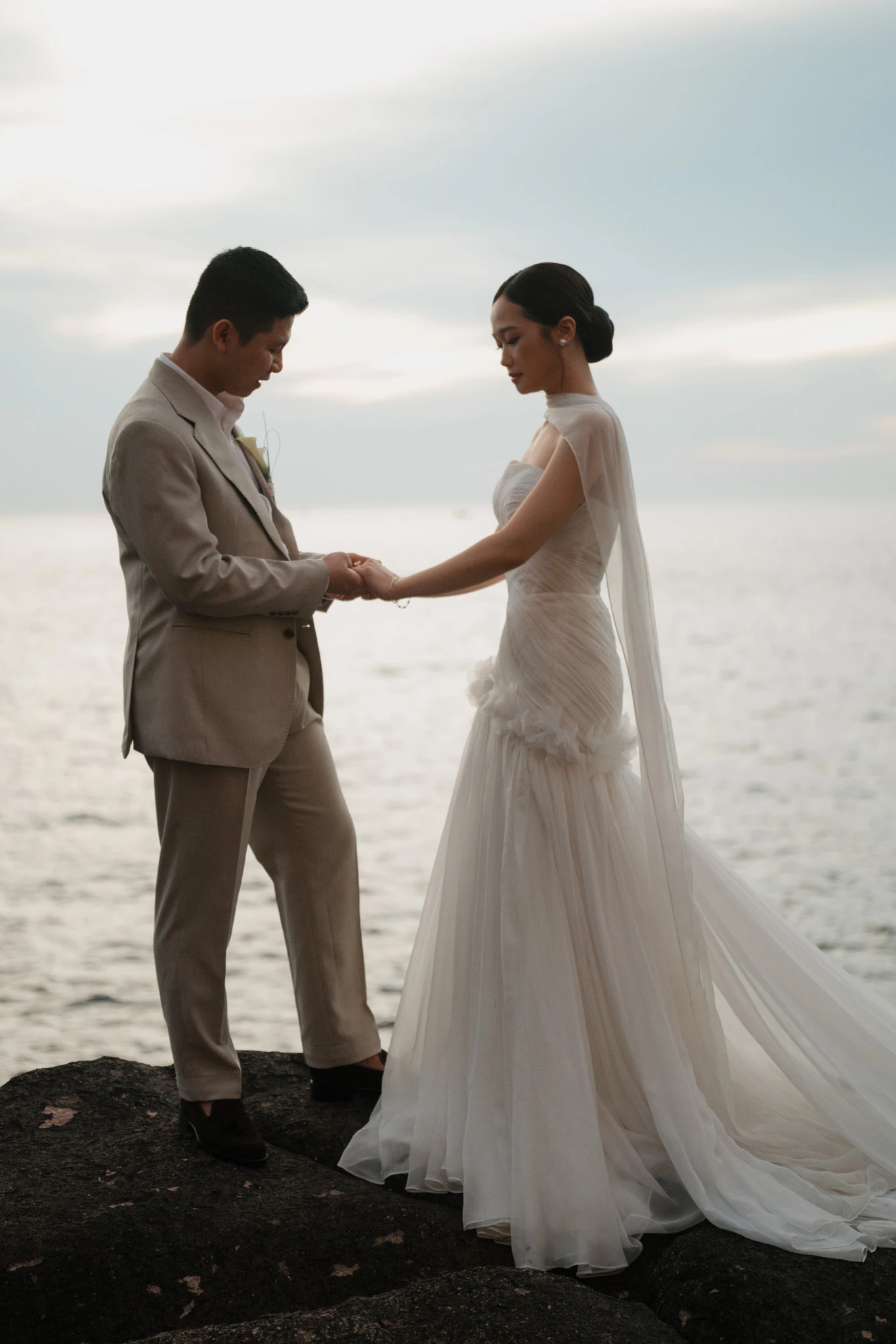 Linh và Bình đứng nắm tay nhau bên biển.