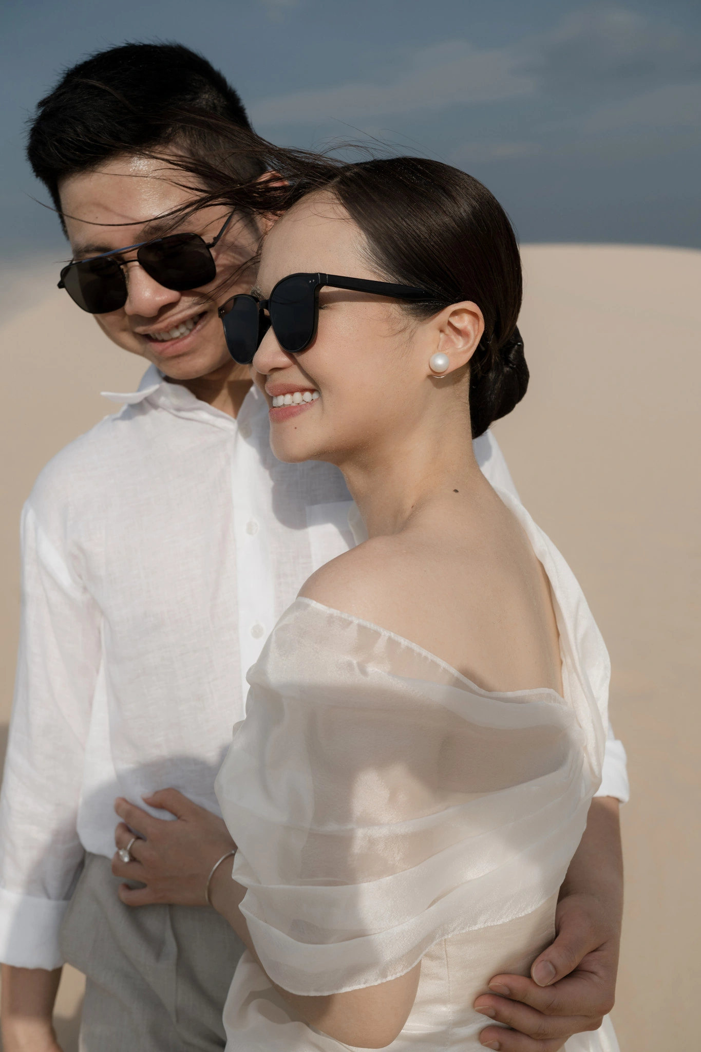 Linh và Bình mỉm cười trên đồi cát.